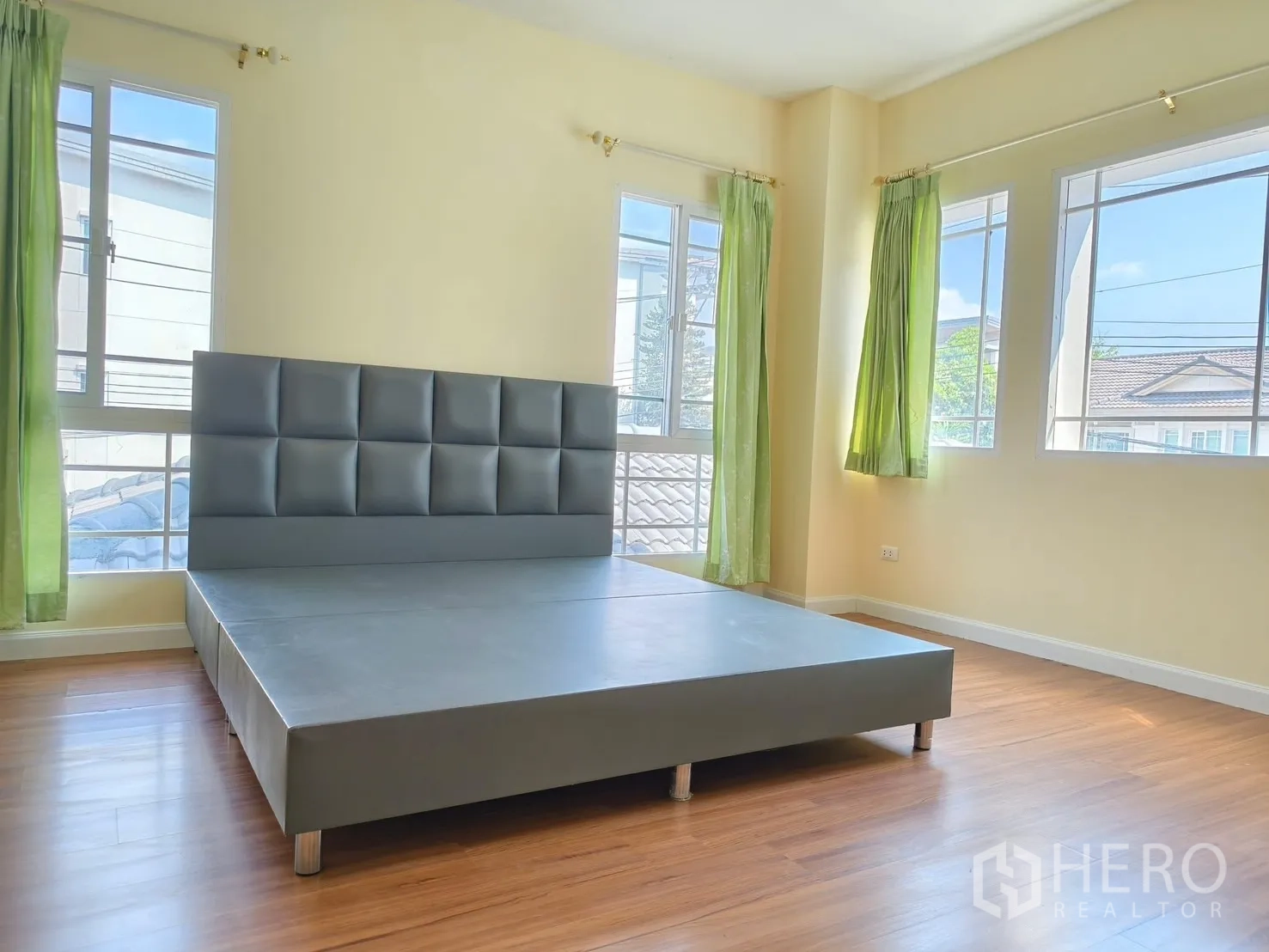 Detached House for rent in Bang Kapi, Bangkok - Corner bedroom with large windows, green curtains and platform bed.