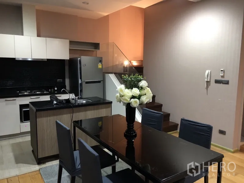 คอนโด ให้เช่าหรือขายในKhlong San, Bangkok - ครัวยุคใหม่ท็อปหินสีดำ ตู้ลอยสีขาว และโต๊ะอาหารติดกับบันไดราวกระจก