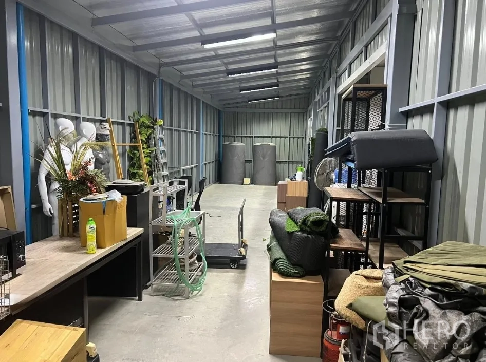 Detached House for rent or sale in Don Mueang, Bangkok - Narrow storage corridor with metal walls holding racks and supplies.