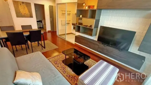 คอนโด ขาย - ห้องนั่งเล่นมีชั้นวางติดผนัง ทีวี และประตูกระจกบานเลื่อนสู่ครัว