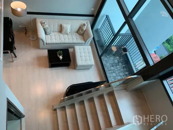 คอนโด ให้เช่า - มุมมองจากด้านบนของพื้นที่นั่งเล่น ระเบียง และบันได พร้อมกระจกสูงโปร่ง