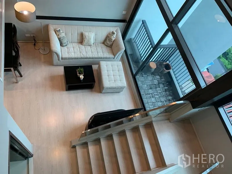คอนโด ให้เช่า - มุมมองจากด้านบนของพื้นที่นั่งเล่น ระเบียง และบันได พร้อมกระจกสูงโปร่ง