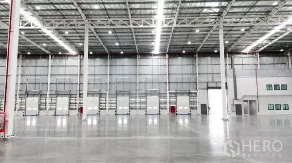 工厂 出租在Samut Prakan - 仓库墙面一排装卸门与调节板，旁有应急设备与人员门