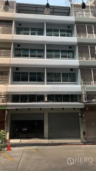 Office Space for rent in Bang Rak, Bangkok - Street view of a commercial building facade showing multiple glass-fronted floors and a parking bay.