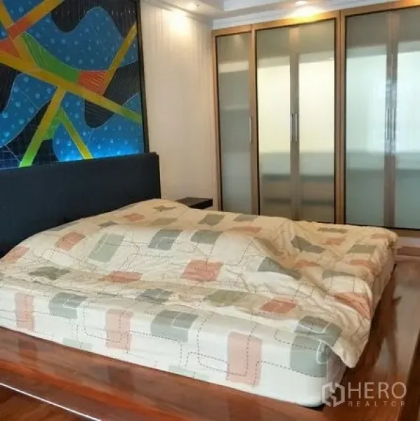 Condominium for rent or sale in Watthana, Bangkok - Master bedroom with a platform bed and sliding frosted‑glass wardrobe doors.