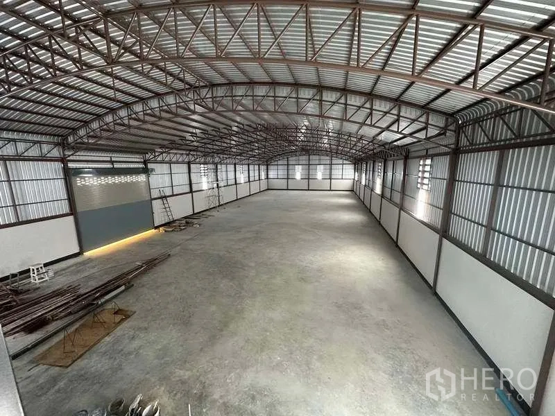 工厂 出租或出售在Sai Noi, Nonthaburi - 通长无柱仓库内部，带卷帘门和充足地面空间。
