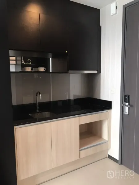 คอนโด ให้เช่าหรือขายในWatthana, Bangkok - ครัวขนาดกะทัดรัด ท็อปหินสีดำ เตาไฟฟ้า อ่างล้าง และตู้ไม้สีอ่อน