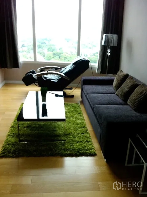 คอนโด ให้เช่าในWatthana, Bangkok - ห้องนั่งเล่นมีโซฟา เก้าอี้เอนกาย และโต๊ะกลาง มองออกสู่วิวเมืองและต้นไม้