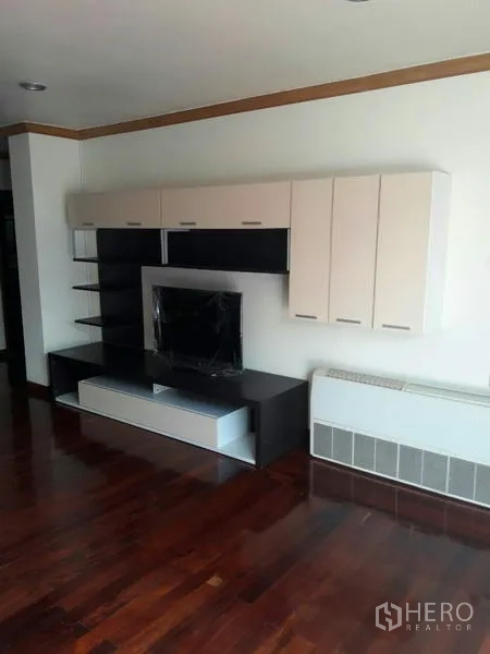 Condominium for rent in Pathum Wan, Bangkok - Modern media wall with cabinets and open shelving over rich hardwood flooring in the living area.