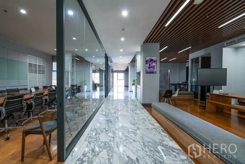 Office Space for rent - Bright corridor with marble walkway, glass partitions, and meeting room.