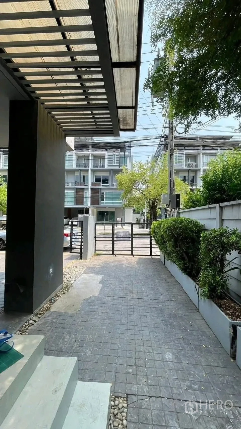 家庭办公室 for rent or sale in Wang Thonglang, Bangkok - 车道与大门通向街道，旁有绿篱。