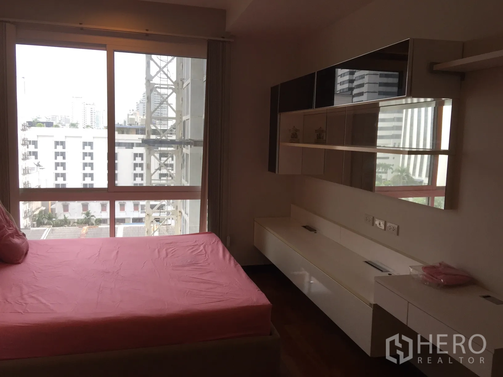 Condominium for rent in Watthana, Bangkok - Bedroom with large window and city view, built-in shelves and a long media counter.
