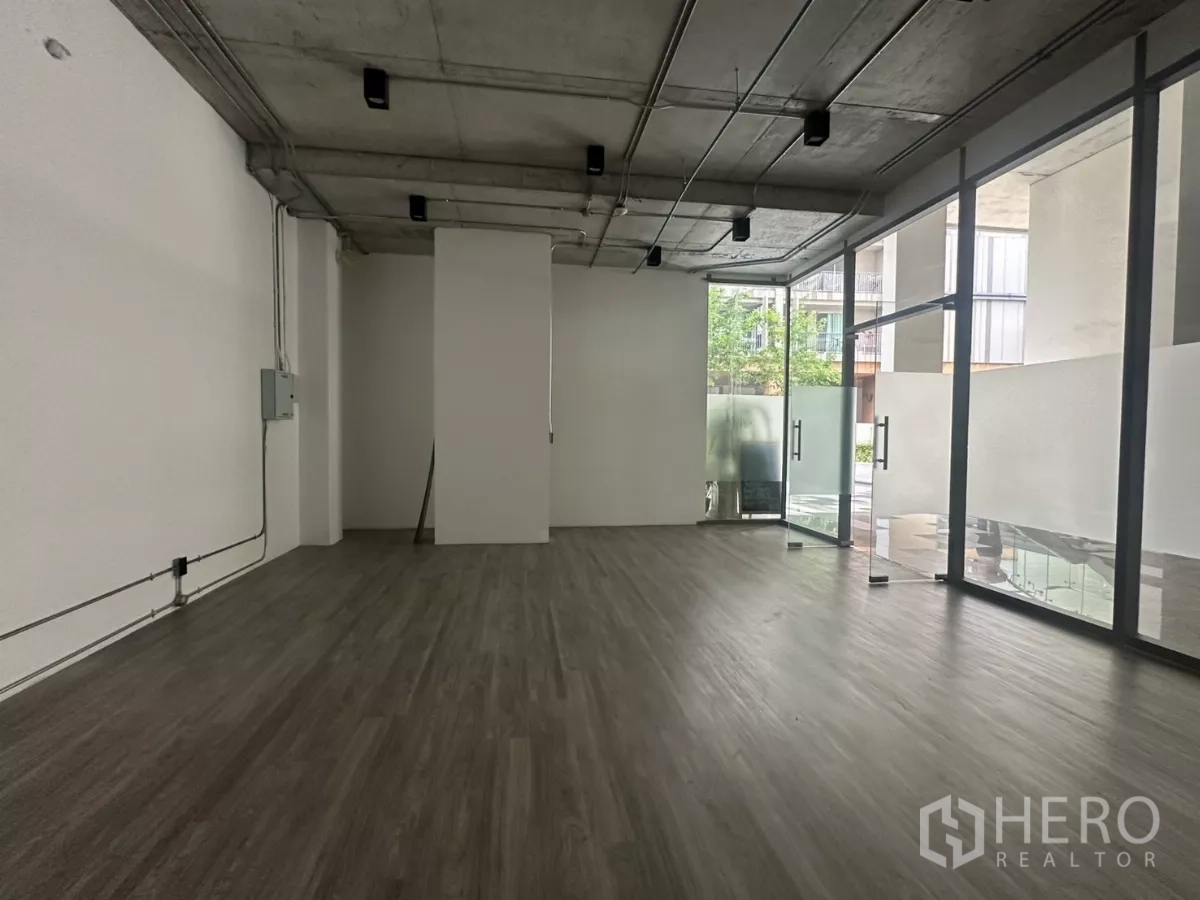 零售空间 出租 - 店铺侧面视角，可见通向中庭的玻璃门、充足采光与乙烯基地板。