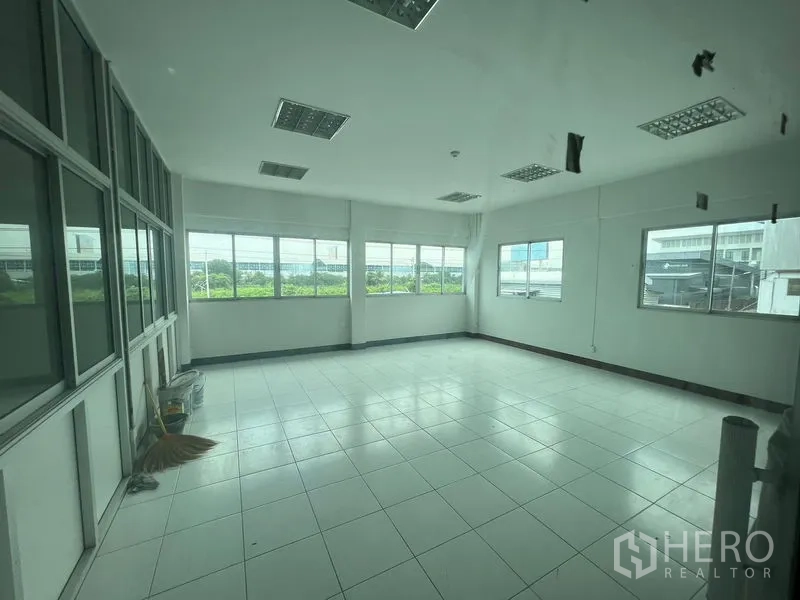 Warehouse for rent in Lat Krabang, Bangkok - Bright mezzanine office room with large windows and tiled floor facing industrial park views.