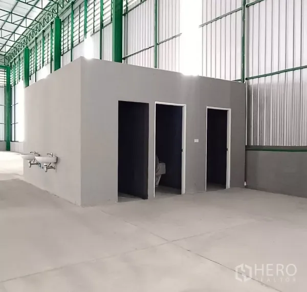 คลังสินค้า ให้เช่าในBang Bon, Bangkok - ภายในโกดังมีห้องน้ำสำเร็จรูป พื้นคอนกรีตเรียบ เสาเหล็กสีเขียว และแผงระบายอากาศ