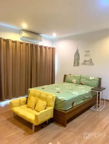 ทาวน์เฮาส์ ให้เช่าในSuan Luang, Bangkok - ห้องนอนหลัก เตียงคู่ โซฟาสีเหลือง พื้นไม้ เครื่องปรับอากาศ และผ้าม่านทึบ