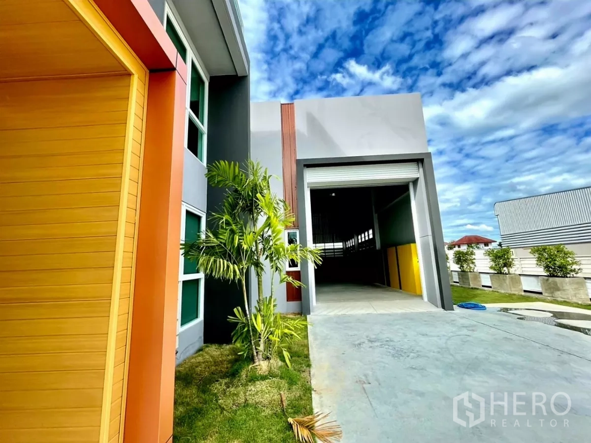 คลังสินค้า ขายในLam Luk Ka, Pathum Thani - ทางขึ้นโหลดสินค้าโกดังพร้อมประตูม้วน ข้างทางเข้าออฟฟิศและต้นปาล์มจัดสวน