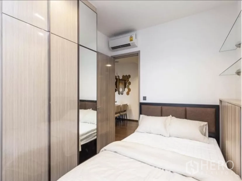 公寓 出租在Ratchathewi, Bangkok - 次卧配双人床、镜面衣柜与空调，可见餐区方向。