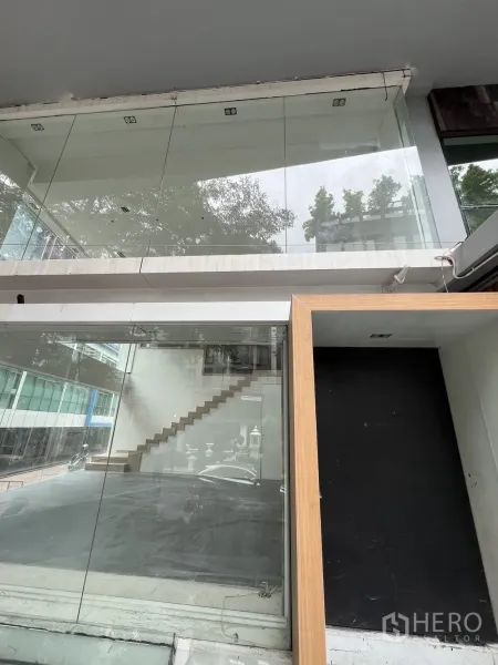 零售空间 出租在Khlong Toei, Bangkok - 临街玻璃立面，带夹层与木质门框的入口。