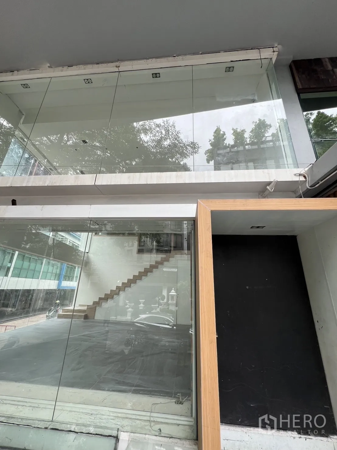 零售空间 出租在Khlong Toei, Bangkok - 临街玻璃立面，带夹层与木质门框的入口。