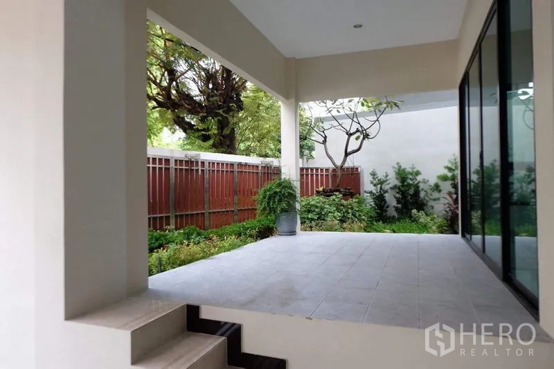 Detached House for sale in Bang Phli, Samut Prakan - Shaded terrace overlooking a small garden and privacy fence with sliding glass wall.