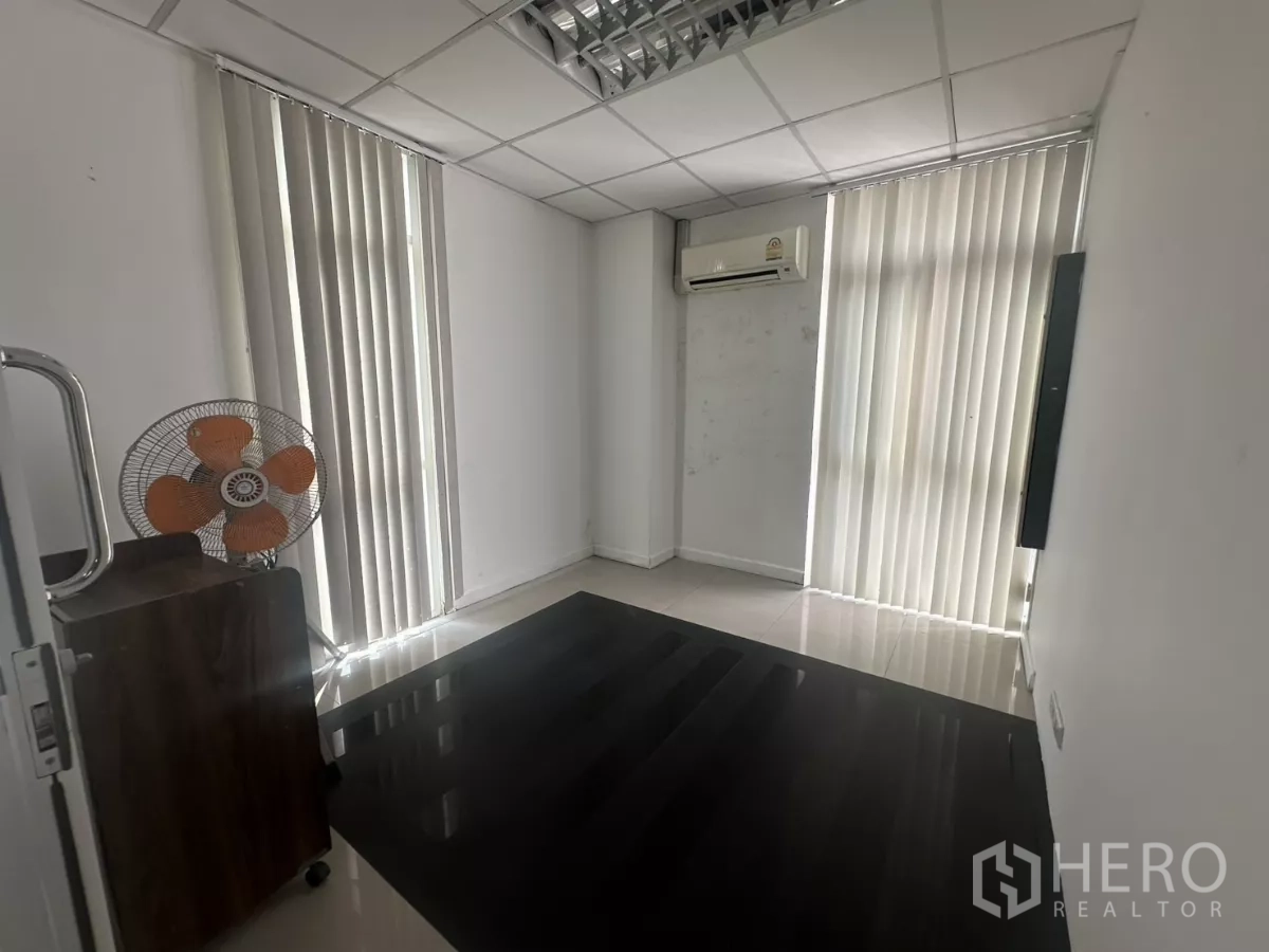 Office Space for rent in Huai Khwang, Bangkok - Compact manager’s office with wall AC, vertical blinds and dark flooring mat.
