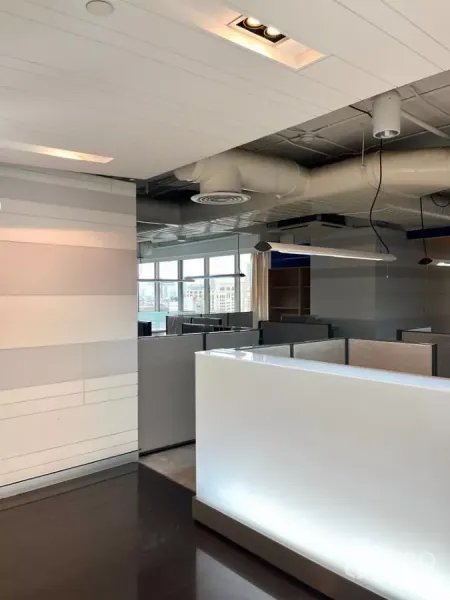 办公空间 出租在Khlong Toei, Bangkok - 设有接待台和隔间工位的现代办公室，大窗与外露风管。