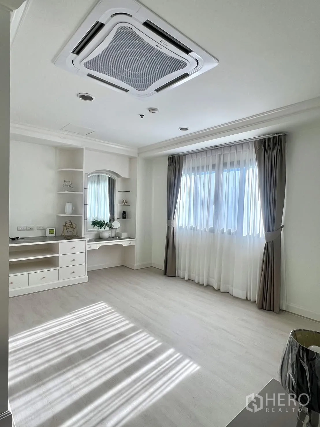 Condominium for rent in Khlong Toei, Bangkok - Bedroom with cassette AC, vanity and double windows with curtains.
