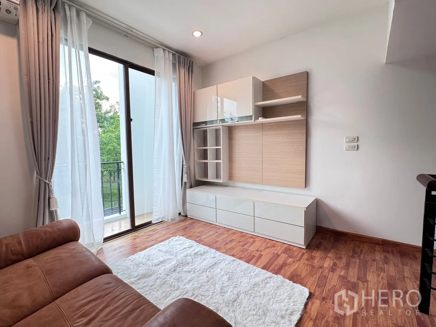 联排别墅 for rent in Phra Khanong, Bangkok - 起居区有沙发、地毯、壁柜与阳台推拉门。