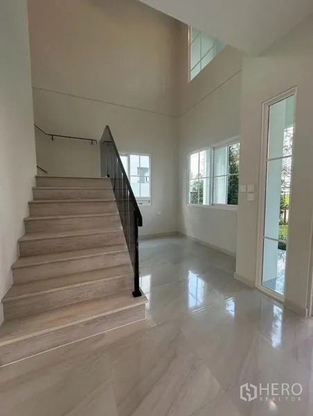 Detached House for rent - Double-height foyer with large windows and a light wood staircase with black railing.