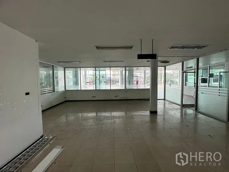 Showroom for rent or sale in Lam Luk Ka, Pathum Thani - Open-plan office with floor-to-ceiling windows facing the street.
