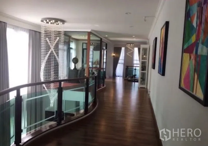 Detached House for sale in Saphan Sung, Bangkok - Upper landing with curved glass railing, wood floors and sculptural crystal lighting.