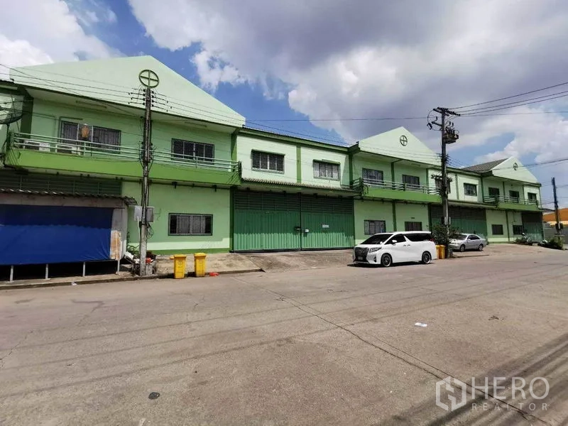 โรงงาน ให้เช่าในSamut Sakhon - แถวอาคารโรงงานสีเขียวติดถนนกว้าง มีที่จอดรถและเสาไฟฟ้า