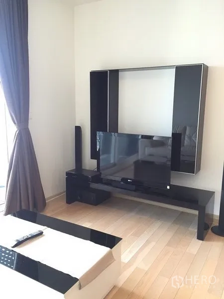 公寓 出租在Khlong Toei, Bangkok - 现代客厅，黑色电视柜与平板电视，旁有大窗与窗帘。