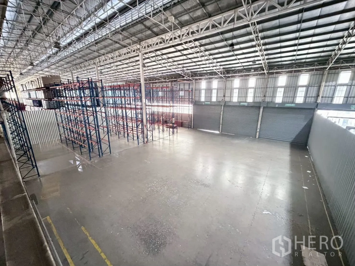 Warehouse for rent in Bang Sue, Bangkok - Open loading zone with several roller shutter doors and a high roof.