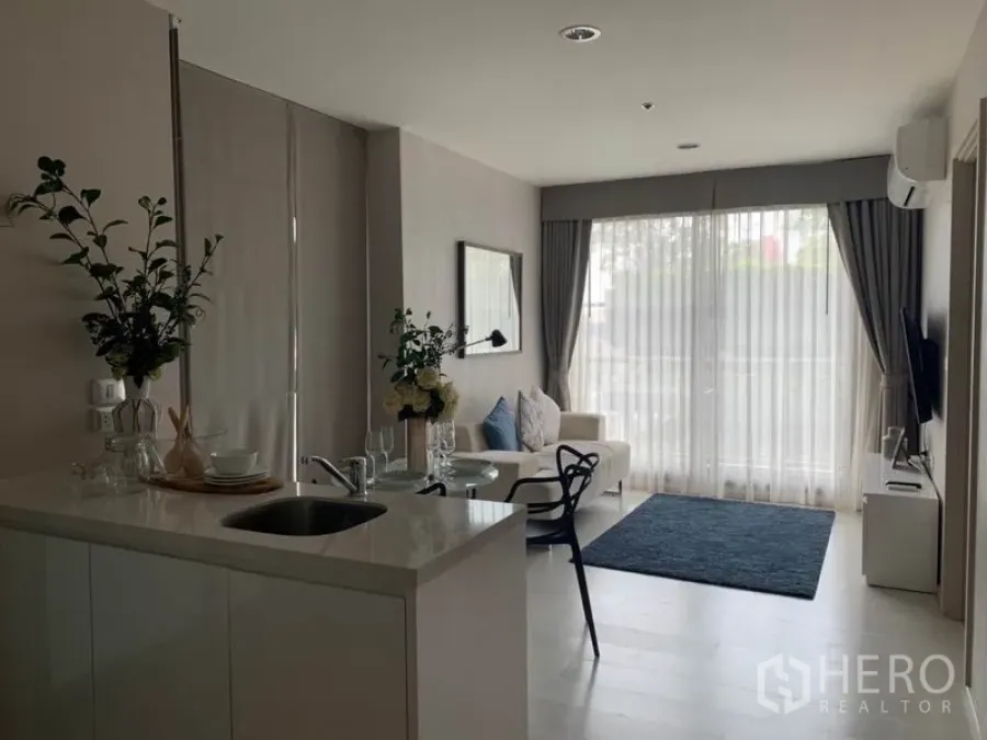 公寓 出租在Khlong Toei, Bangkok - 采光充足的开放式客厅，配小厨房、沙发与大推拉玻璃门的现代公寓