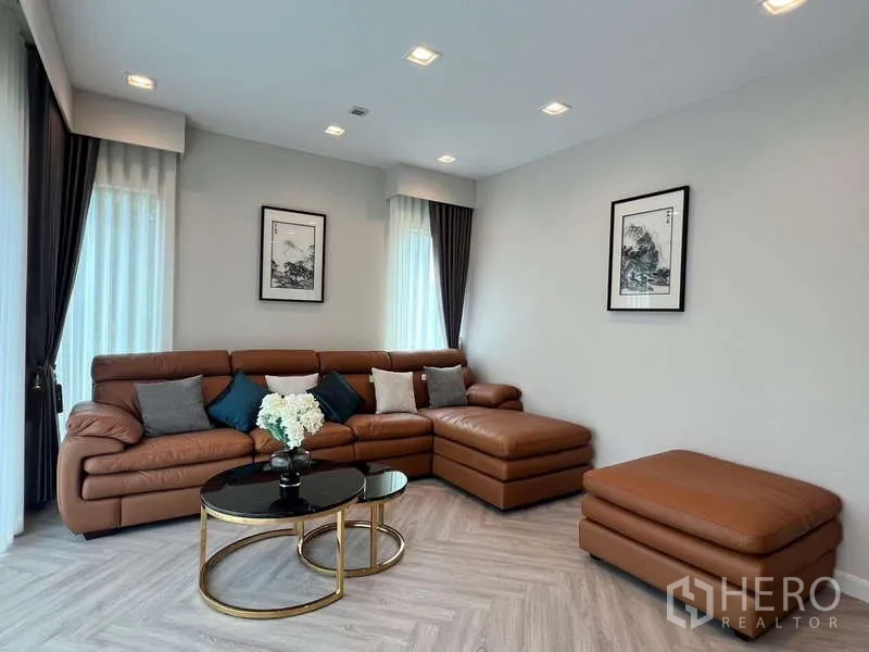 บ้าน ให้เช่าหรือขายในLat Krabang, Bangkok - ห้องนั่งเล่น โซฟาหนังสีน้ำตาลรูปตัวแอล พร้อมโต๊ะกลางทรงกลมสีดำทอง