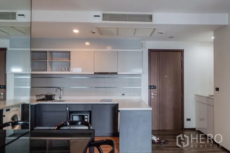 公寓 出租在Khlong Toei, Bangkok - 厨房台面下的嵌入式洗衣机，旁为电磁灶。