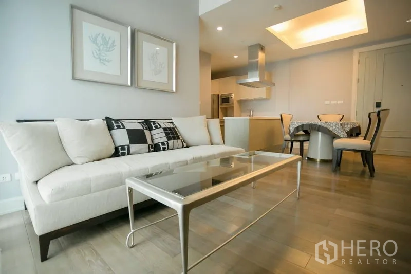 คอนโด ให้เช่าในPathum Wan, Bangkok - ห้องนั่งเล่นสว่าง เฟอร์นิเจอร์โทนครีม โต๊ะกลางกระจก พื้นไม้ ต่อเนื่องสู่ครัวและมุมทานอาหาร