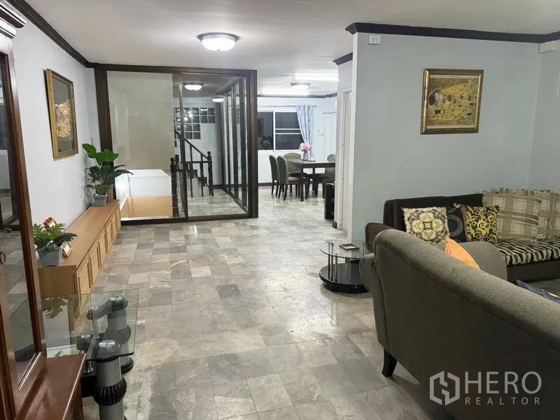 联排别墅 出租在Prawet, Bangkok - 开放式客餐厅，玻璃围合楼梯与瓷砖地面。