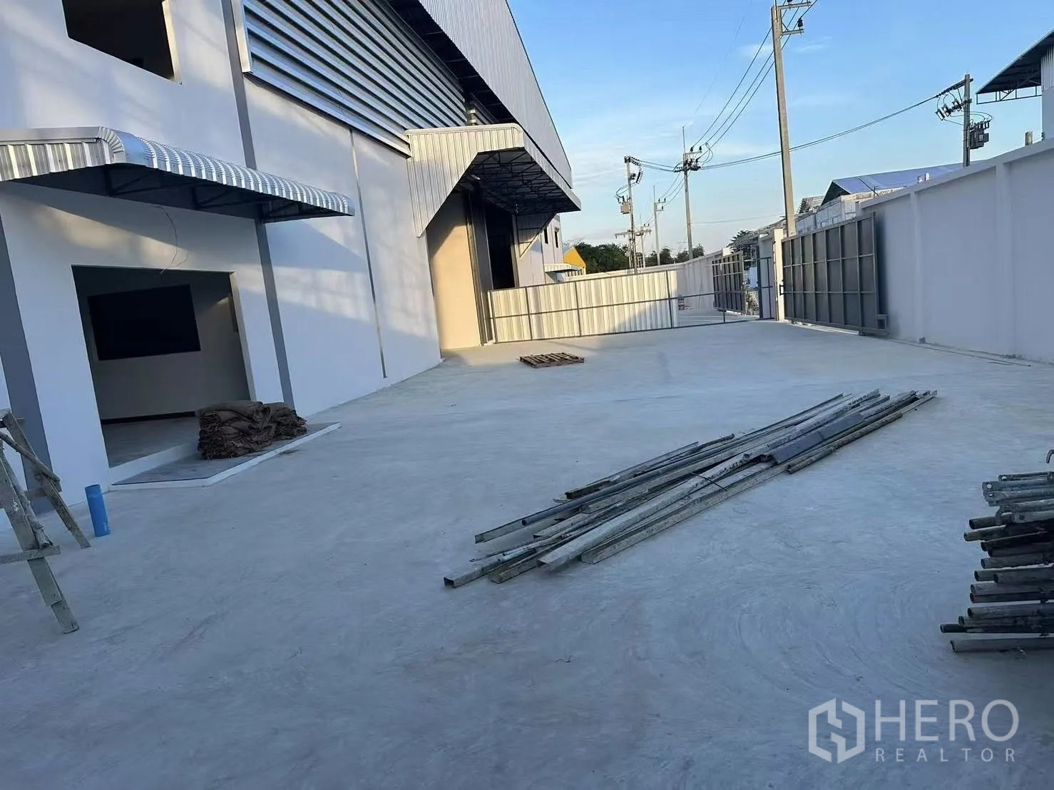 工厂 出租在Nong Khaem, Bangkok - 前场装卸区宽敞，整片混凝土铺面，配有雨棚与推拉大门，便于卡车进出。
