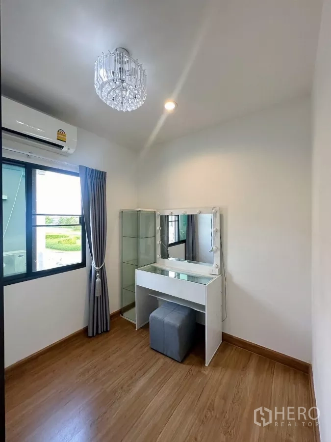 Townhouse for rent in Bang Phli, Samut Prakan - Cozy secondary bedroom with vanity table, glass display cabinet, air conditioner and window view.