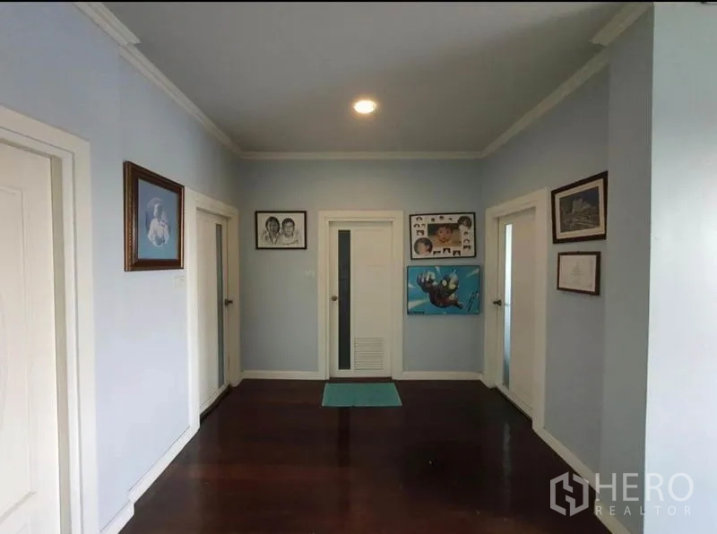 独立式住宅 出售在Sai Mai, Bangkok - 二楼走廊，浅蓝色墙面，多扇门与抛光木地板。