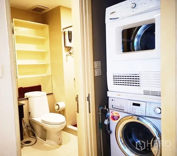 公寓 出租在Khlong Toei, Bangkok - 洗衣区配叠放式洗衣机和烘干机，旁有客卫与置物架。