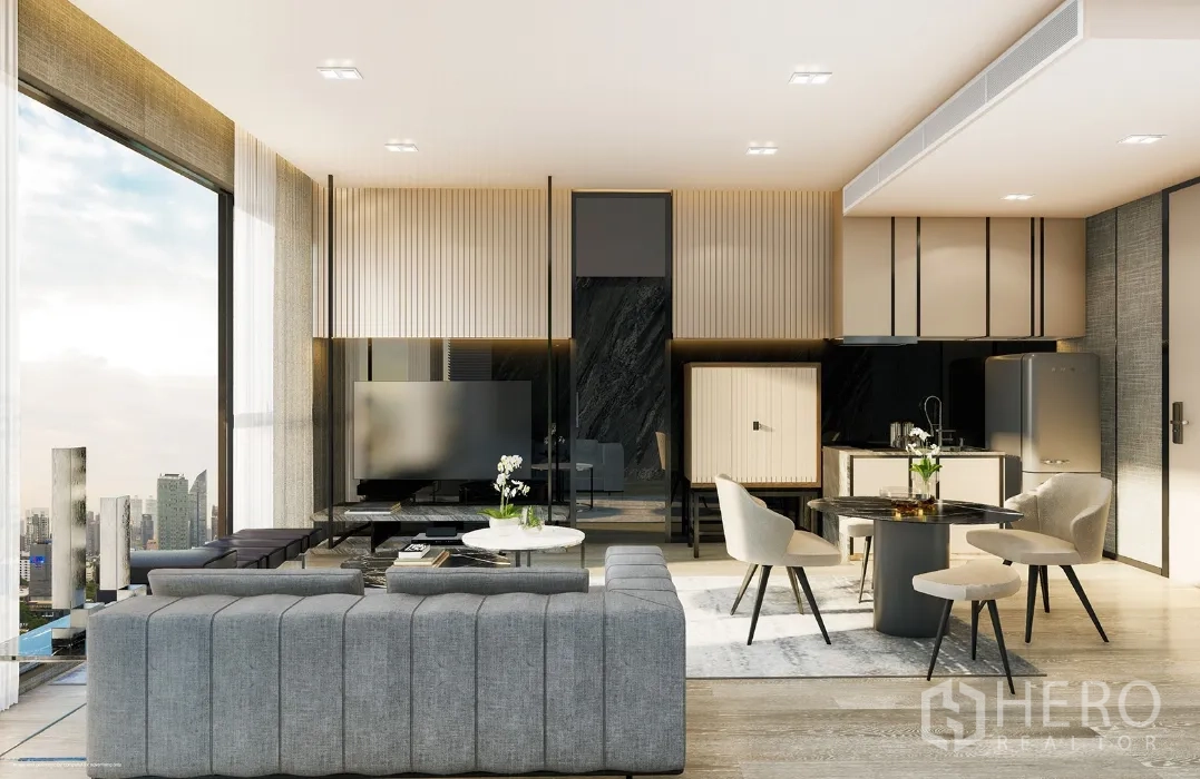 Condominium for sale in Watthana, Bangkok - Open‑plan living room with grey sofa, dining set and sleek kitchenette facing large windows and Bangkok skyline views.