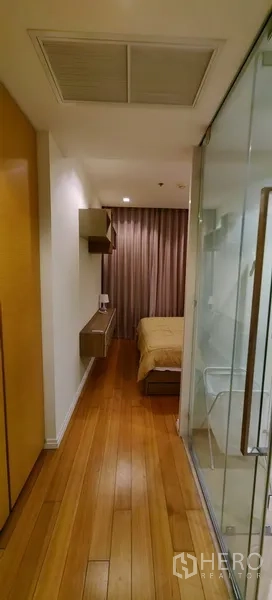 คอนโด ให้เช่าในKhlong San, Bangkok - โถงทางเดินสู่ห้องนอน เห็นประตูกระจกห้องอาบน้ำและพื้นไม้ในคอนโดสมัยใหม่