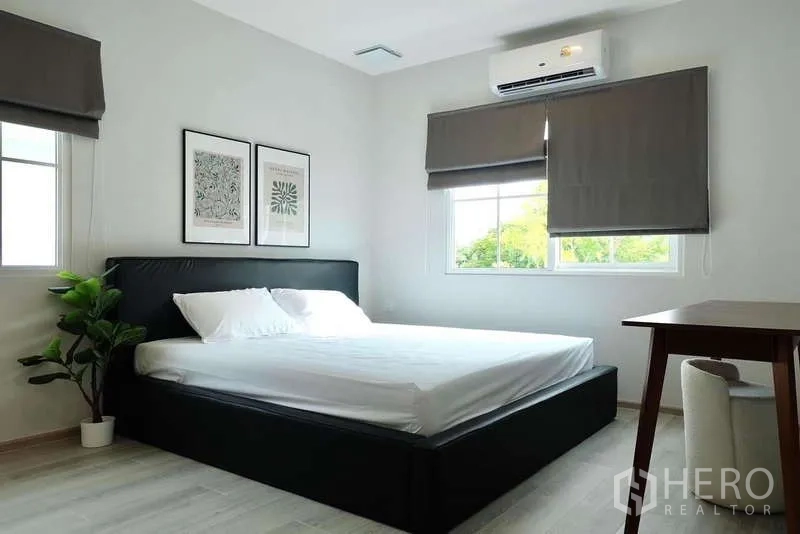 Detached House for rent in Bang Phli, Samut Prakan - Sunlit bedroom with double bed, AC, two windows and potted plant.