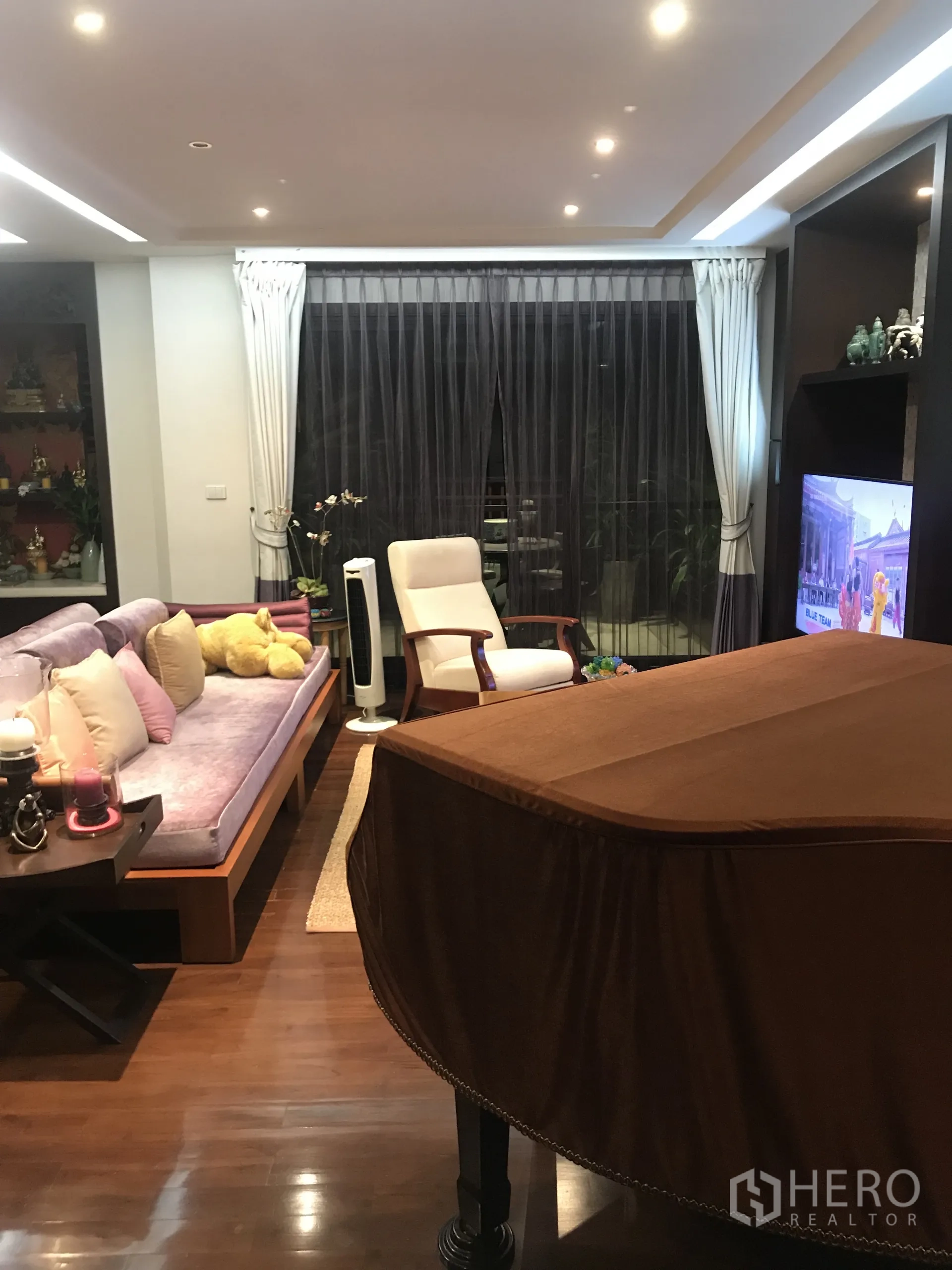 Condominium for sale in Yan Nawa, Bangkok - Living room with grand piano, sofa seating and floor-to-ceiling curtains by the balcony.