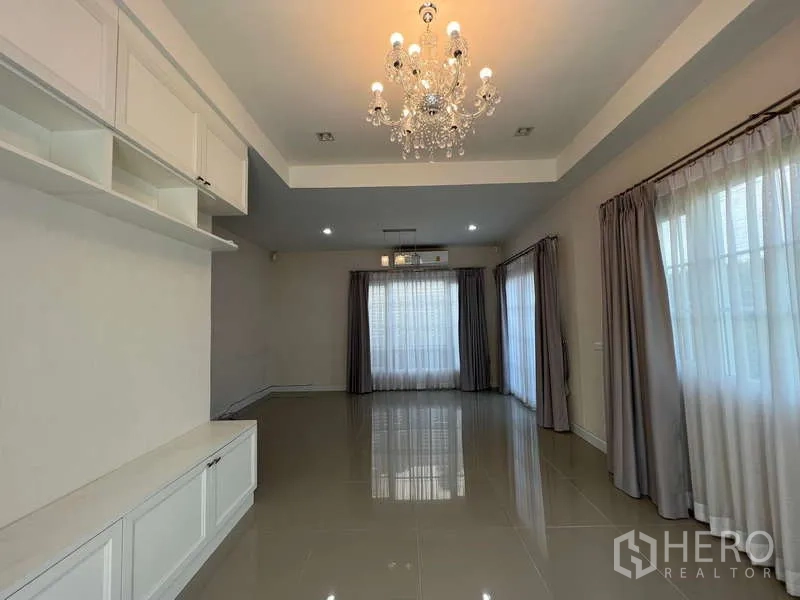 บ้าน ให้เช่าหรือขายในKhan Na Yao, Bangkok - ห้องนั่งเล่นสว่าง โคมระย้า พื้นกระเบื้องเงา และผ้าม่านเต็มบาน