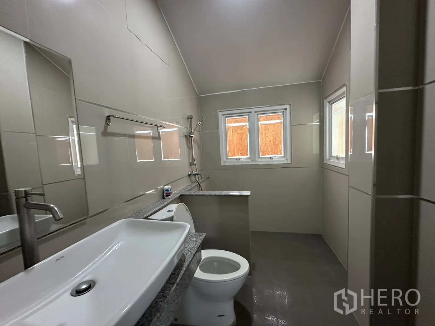 Home Office for rent in Watthana, Bangkok - Bathroom with long granite vanity, vessel sink, toilet and walk-in shower under twin windows.